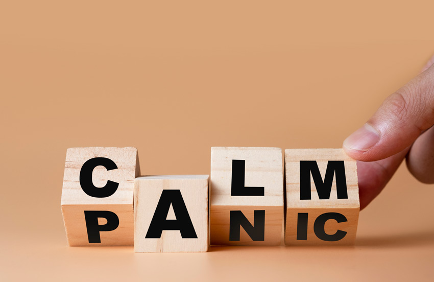 Person’s hand flipping wooden cubes from word Panic to Calm